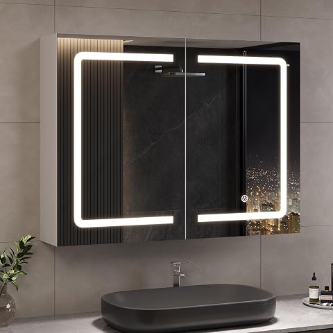 Armoire de toilette blanche à deux portes miroir, éclairage LED et prise intégrée au-dessus d’une vasque claire.
